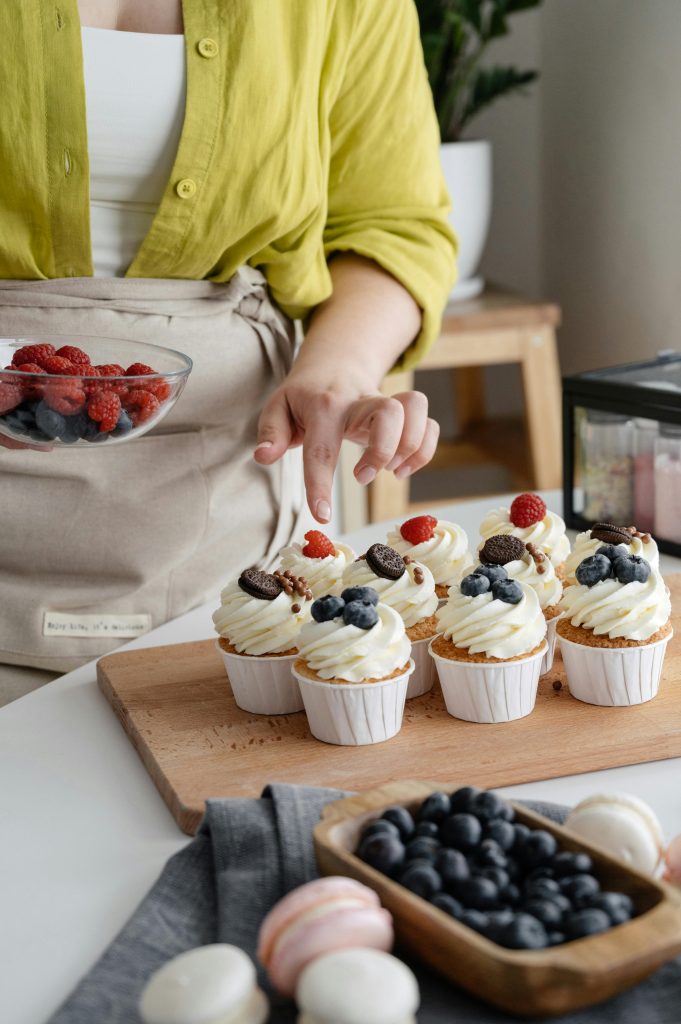 Close-up of cupcakes being decorated with fresh raspberries and blueberries